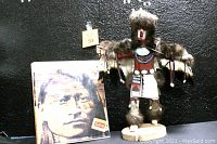 Full view of the Native American figurine statue standing with the companion book propped up for scale and context.