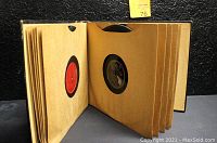 Open record binder showing pages with single 78 RPM records mounted inside each sleeve, visible at center holes and colored labels.