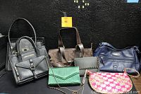 View of seven women's purses with assorted colors and styles against a black background