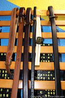 Photo of six assorted leather belts in various colors, hung on a wooden rack.