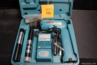 Makita cordless drill, two batteries, charger and drill bits in open teal blue carrying case
