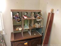 View of dollhouse with dolls lying in different rooms, showing wallpapered interiors and window cutouts.