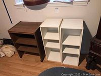 Three bookcases aligned side by side: one brown and two white with shelves.
