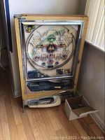 Full front view of wooden-framed pachinko machine with ball box at base