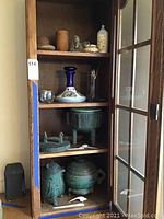 Full view of glassware and metal containers inside wooden cabinet