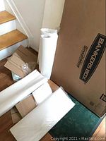 Unused Bankers Box and rolled packing paper on floor near stairs