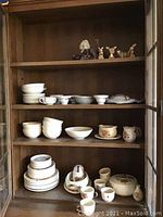 Full shelf view showing Poppytrail china dishware including plates, bowls, gravy boat, tureen, platter, cream and sugar, and teacups with saucers alongside animal figurines on top shelf.