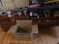 Wide view showing kitchenware including cooking pots, various kitchen utensils, collectible glasses, coffee mugs and Bundt pans arranged on shelves and surface.