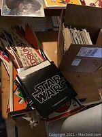 Stack of movie soundtrack albums and sports pennants with box of magazines visible