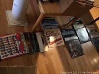 Photo showing multiple vinyl records laid out on wooden floor surface, featuring colorful and illustrated album covers with artists such as Cheech And Chong and Disney themed records.