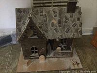 Wooden painted dollhouse with a detailed roof and base, showing signs of age and wear.