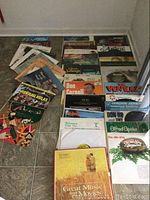 Photo of full lot of 26 vinyl records arranged on floor, showing multiple album covers and titles.