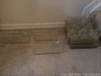 Several ribbed rectangular glass trays stacked on carpet floor