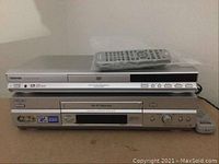 Toshiba DVD player model SD3950 and Sony SLV-N750 VCR unit stacked with Toshiba DVD remote on top and VCR remote to the side.