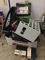 View of various office supplies including black plastic and metal file organizers, green hanging file folders, and a box containing more items.