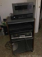 Overall view of the stereo cabinet with electronics stacked, showing the complete set and shelving, audio/video units, and cabinet details.