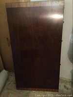 Full view of rectangular dark wood table leaf with a lighter wood grain border on bottom edge.