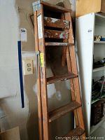 Wooden 6-foot step ladder with chipped paint and scuffed wood steps.