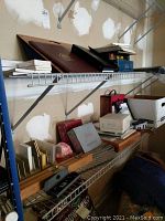 Shelf of wooden organizers and boxes containing office supplies along with boxed games and a lapdesk
