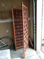 Partially folded room divider leaning in garage with bicycle wheel visible