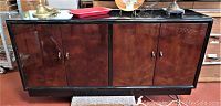 Front view of Henredon Scene Three sideboard showing black lacquer top and burled wood doors with brass handles.