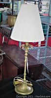 Full view of brass table lamp with tan tapered shade showing overall condition and build
