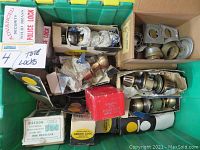 Box containing several vintage Arrow and Fox Police Lock door locks, some in original boxes, along with miscellaneous trim rings and lock hardware parts inside a green tote.