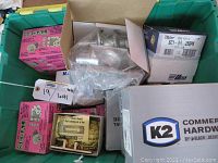 Top view of green heavy tote filled with multiple boxed door lock components including pink Segal packages, K2 hardware box, and Taylor key blanks box.