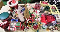 Wide view of various Christmas decorations spread out on a table including tins, ornaments, figurines, and garlands.