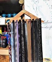 View of 15 ties hanging on wooden Woodlore rack showing variety of colors and patterns including stripes, checks, and solids.