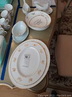 Top view of the Tuscan Princess china pieces laid out on a table showing two serving platters, two gravy bowls, and several smaller pieces with a floral and gold trim pattern.