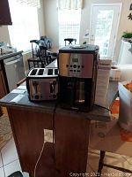 Photo shows the Black and Decker toaster and Krups coffee maker placed on kitchen counter near sink and window, well-lit environment