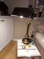 Full view of the metal desk lamp positioned on a stack of books showing its overall condition and design.