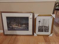 Two framed items on floor; one large Fred Swan print with a winter landscape and one smaller gold-tone frame with corner protectors.