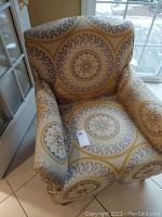 Full view of a cloth armchair showing circular medallion design upholstery and chair dimensions roughly 30x30x35 inches