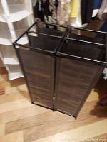 Two black plastic frame shoe racks with mesh sides on wooden floor.