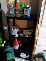 Shelf with assorted cleaning products and paint supplies including a power sander below