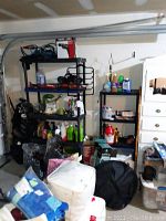 Two plastic shelving units filled with various boxed and bottled household and garage items, shown in a garage setting.