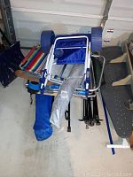 Photo showing camp and beach chairs folded and stacked with the beach umbrella in a carrying bag placed on top