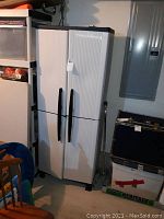 Closed plastic storage cabinet with white textured double doors and black handles.