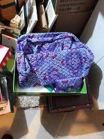 Photo of large purple patterned Vera Bradley bag alongside matching clutch bag inside a box