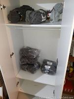 Yarn skeins stored on white shelving, including Bernat Yarnspirations and Mainstays Chenille Chunky yarn in plastic packaging