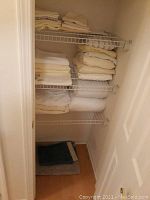 Full view of linen closet shelving packed with folded linens including towels and pillow cases.