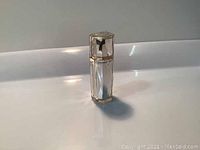 Front view of the clear faceted Shiseido Clé de Peau Beauté The Serum 6ml bottle standing on white surface.