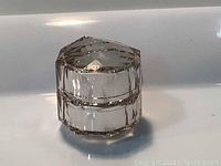 Close up of the small crystal-like jar for Shiseido Cle de Peau Beaute The Cream 5ml, showing the lid and reflective surface details.