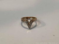 Front view of one V-shaped ring showing gold and silver tones with crystal chatons embedded on the V section.