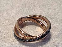 Close-up of rose gold tone Swarovski ring featuring a crisscross design with one band set with blue crystals.