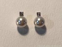 Front view of Swarovski earrings showing white pearl and square crystal with rhodium plating.