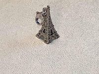 Close-up image of a silver-tone Eiffel Tower charm decorated with clear crystal pavé, showing detailed design.
