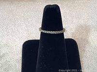 Front view of Swarovski ring with clear crystal chatons on gold rhodium plated band shown on black velvet finger stand.